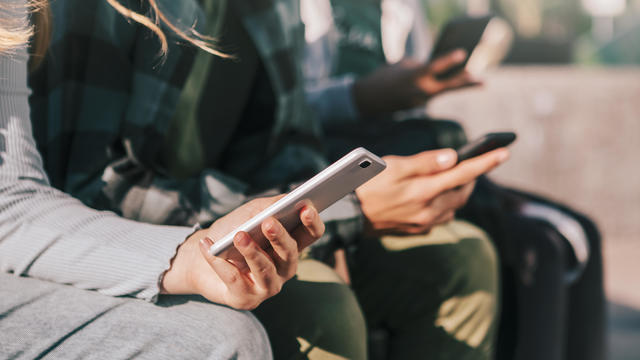 Detail of teenagers watching with their mobile phones 