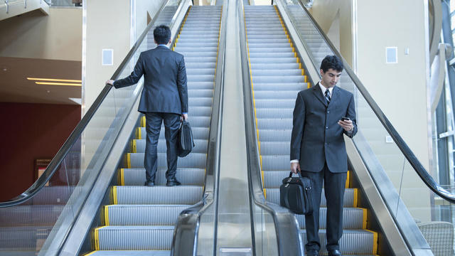 Businessmen standing on escalators 