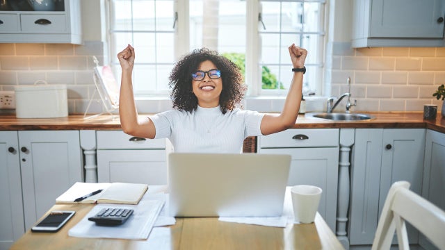 Shot of a beautiful young woman looking happy while working on her laptop at home 