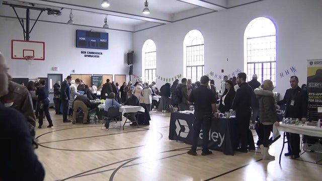 Multiple tables are set up in a gymnasium for a job fair. 