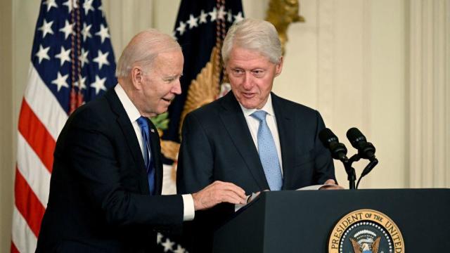 President Biden helps former President Bill Clinton find his notes during an event marking the 30th anniversary of the Family and Medical Leave Act in the East Room of the White House on Feb. 2, 2023. 