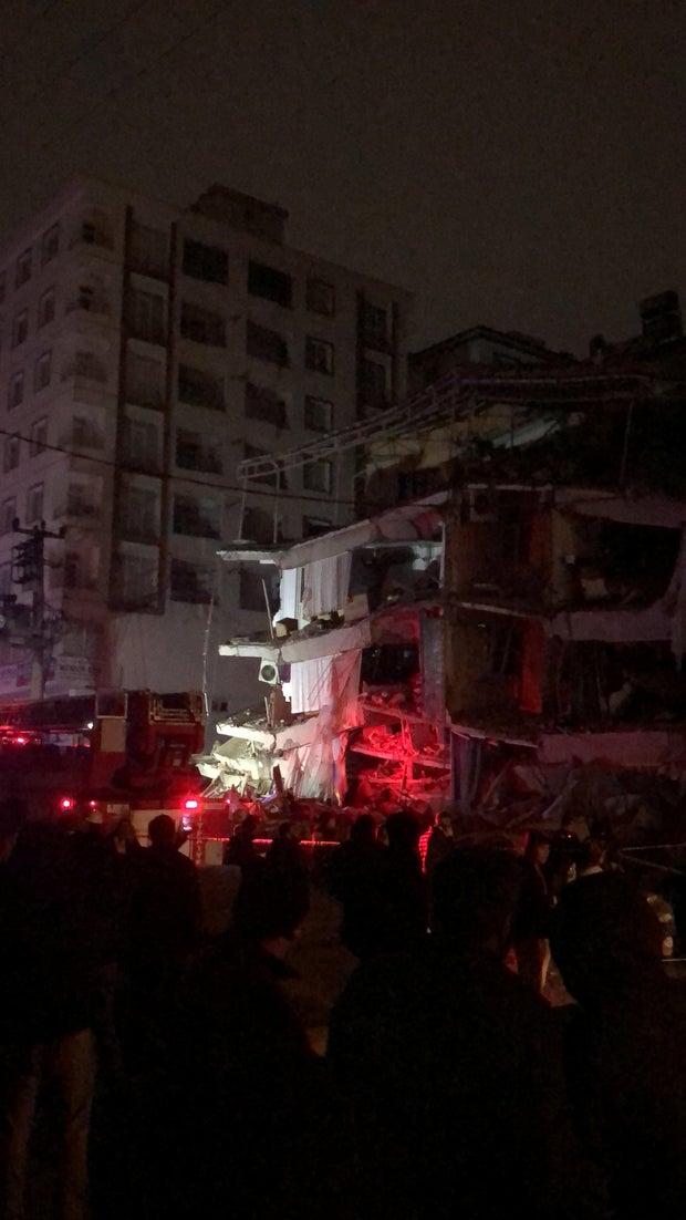 People gather near a building that collapsed after an earthquake in Diyarbakir