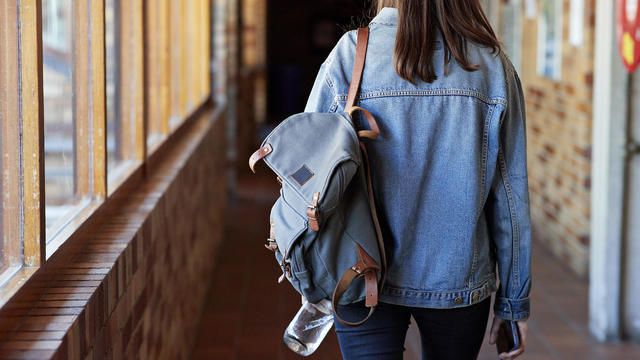 Young woman with backpack walking in corridor 