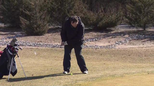 A golfer hits a golf ball. 