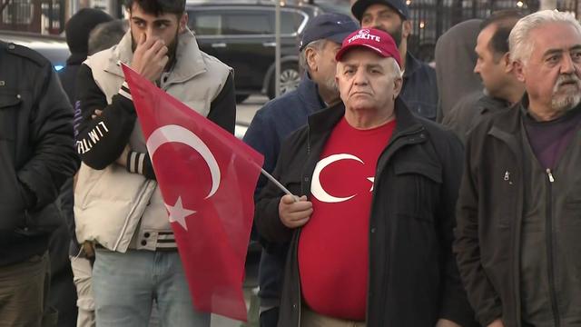 A man holding the Turkish flag and wearing a shirt with the Turkish flag stands at a vigil in Paterson. 