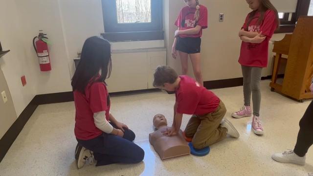 A middle schooler practices CPR on a dummy. 