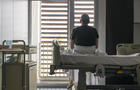 Man sits on hospital bed and looks out of the window 