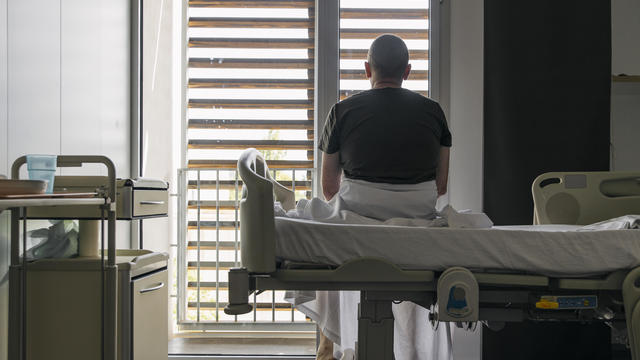 Man sits on hospital bed and looks out of the window 
