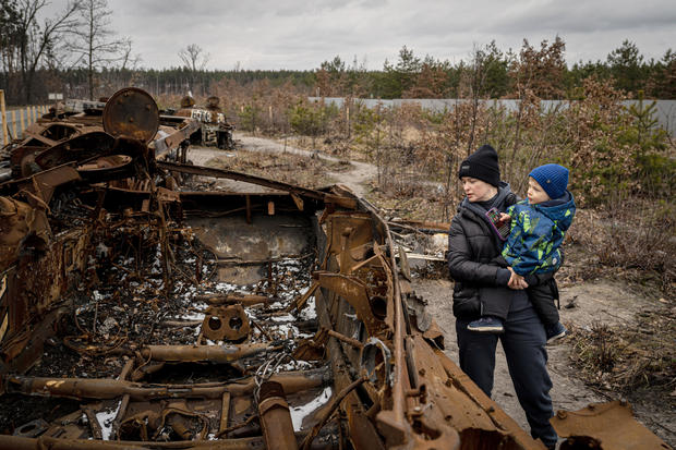 A family in Ukraine examines the remains of a Russian tank destroyed in the war 