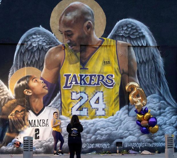FILE PHOTO: FILE PHOTO: A fan poses by a mural of late Kobe Bryant, who perished one year ago alongside his daughter and seven others when their helicopter crashed into a hillside, in Los Angeles 