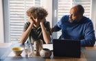 Father talking to son while teaching him at table 