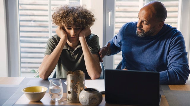 Father talking to son while teaching him at table 