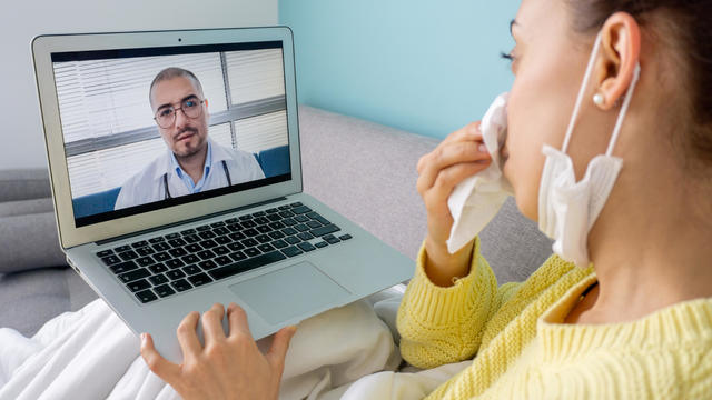 Sick woman at home talking to her doctor via video call 