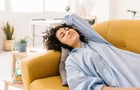 Smiling young woman with eyes closed resting on sofa at home 