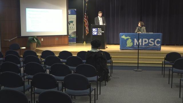 Man speaking at podium during public hearing hosted by the Michigan Public Service Commission Host over the proposed 679 area code 