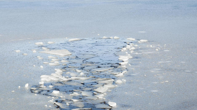 Hole in the thin ice. Someone fell through the ice. Dangerous concept. Freezing and melting time for ice on the water reservoirs in winter. 