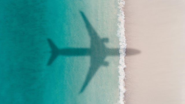 Aerial shot showing an aircraft shadow flying over an idyllic beach scene, Barbados 