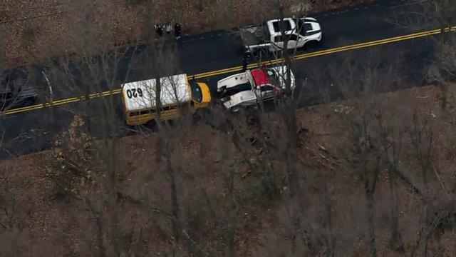 An aerial shot of a short yellow school bus hooked up to a tow truck. 