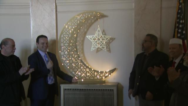 Paterson Mayor Andre Sayegh and other officials stand next to a lit crescent moon light. 