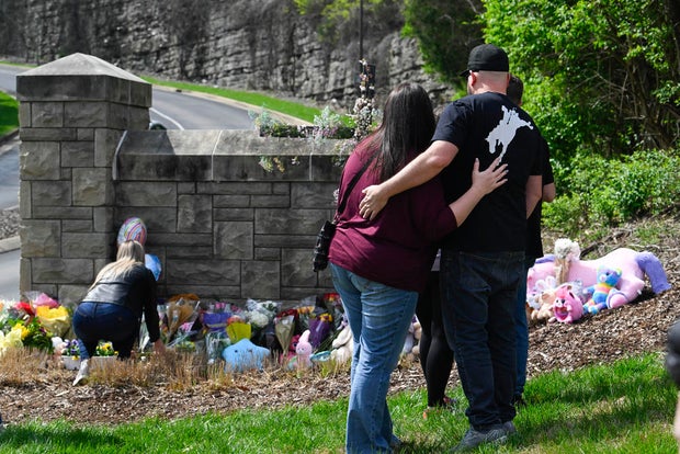 People gather at an entry to Covenant School, which has become a memorial for shooting victims, March 28, 2023, in Nashville, Tenn.