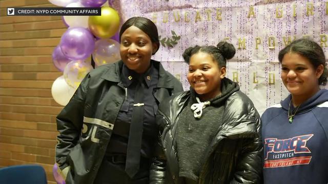 A female NYPD officer poses for a photo with two young girls. 