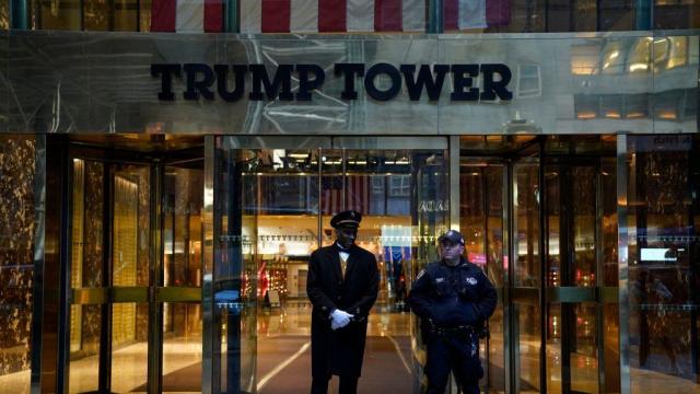 A police officer and a building employee stand in front of Trump Tower in New York on March 30, 2023. 