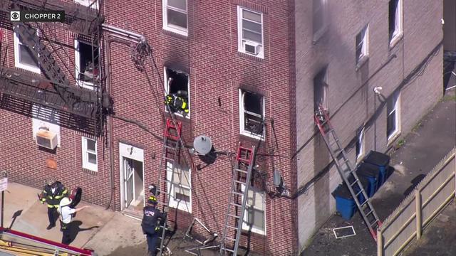 A firefighter leans out a broken window of an apartment building. 