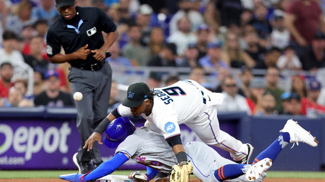 Brandon Nimmo #9 of the New York Mets slides safely into third base against Jean Segura #9 of the Miami Marlins during the sixth inning on Opening Day at loanDepot park on March 30, 2023 in Miami, Florida. 