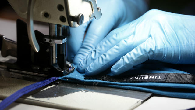 Close up of hands in blue gloves at sewing machine 