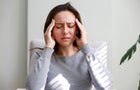 Shot of a young woman holding her head in discomfort due to pain at home 