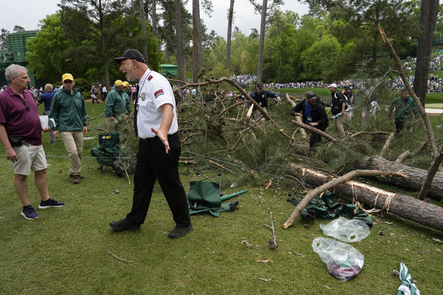 A security guard is seen moving people away from a tree that blew over on the 17th hole at the Masters golf tournament. 