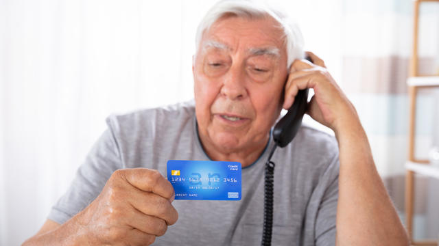 Man With Credit Card Using Landline Phone 