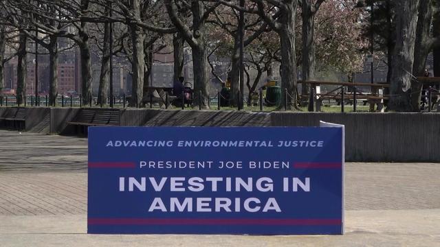 A sign reading "Advancing environmental justice. President Joe Biden. Investing in America" in Riverbank State Park. 