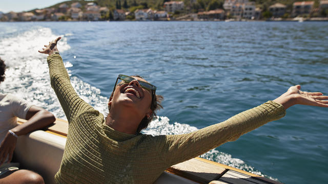 Happy woman with arms raised in motorboat 