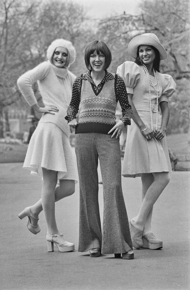 Mary Quant with two models at the launch of her Ginger Group autumn collection in London, UK, 2nd May 1972. Lorain on the left wears a knitted sweater and skirt in pink mohair called 'Sugarplum', and Freddie on the right wears a pink woolen flannel dress with puffed sleeves and a matching hat, called 'Marshmallow'. 