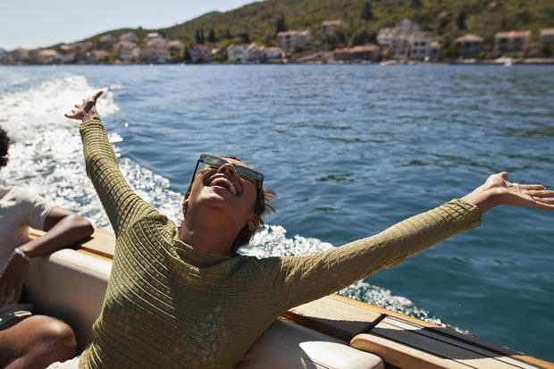Happy woman with arms raised in motorboat 