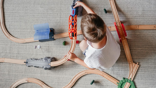 Little boy playing iron wooden track at home on the floor. 