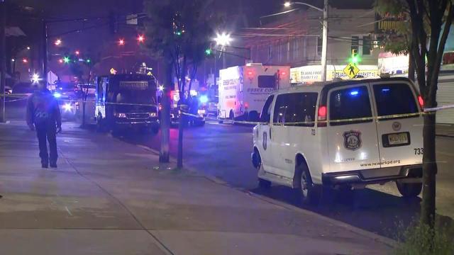 Police vehicles parked behind crime scene tape outside a food market. 