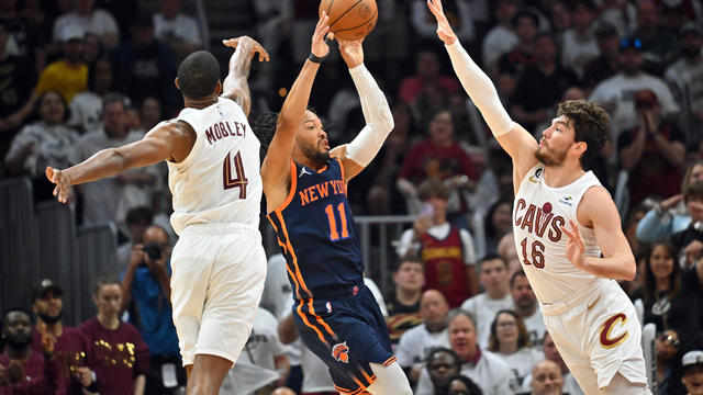 Jalen Brunson #11 of the New York Knicks passes between Evan Mobley #4 and Cedi Osman #16 of the Cleveland Cavaliers during the fourth quarter of Game One of the Eastern Conference First Round Playoffs at Rocket Mortgage Fieldhouse on April 15, 2023 in Cl 