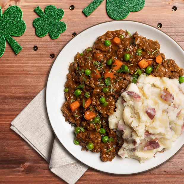 Shepherd's Pie with Fresh Herbs, plated on a counter with a napkin and green four leaf clover decorations nearby
