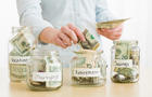 Teenage girl (16-17) filling jars with various labels with US dollars 