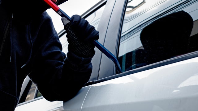 Masked burglar trying to get into a car 