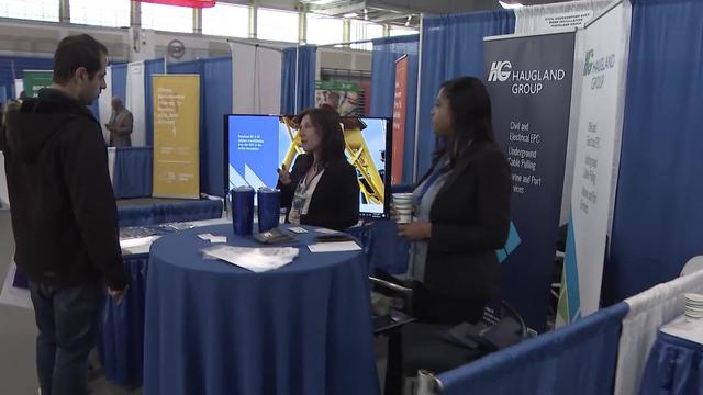 Recruiters speak to a job seeker at a job fair. 