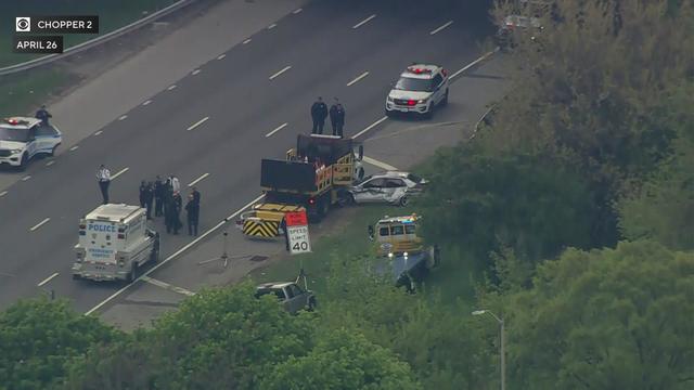 An aerial shot of police surrounded construction equipment on the shoulder of the Grand Central Parkway. 