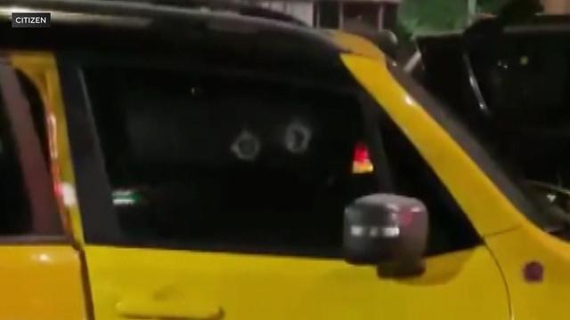 Two holes can be seen in the front passenger's side window of a yellow vehicle. 