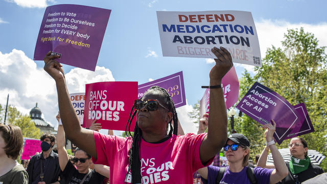 Activists holding abortion rights signs shout slogans during 