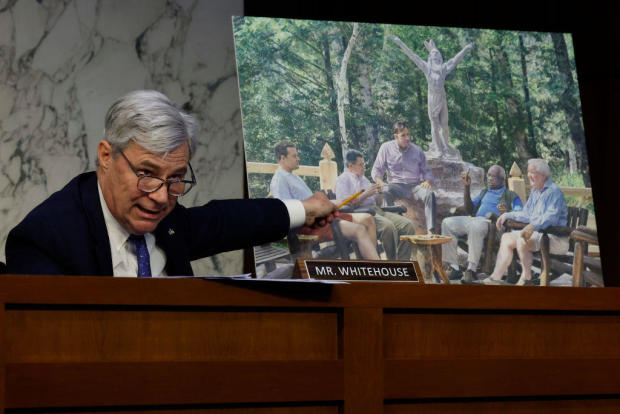 Senate Judiciary Committee member Sen. Sheldon Whitehouse displays a copy of a painting featuring Supreme Court Justice Clarence Thomas alongside other conservative leaders during a hearing on Supreme Court ethics reform on May 2, 2023. 