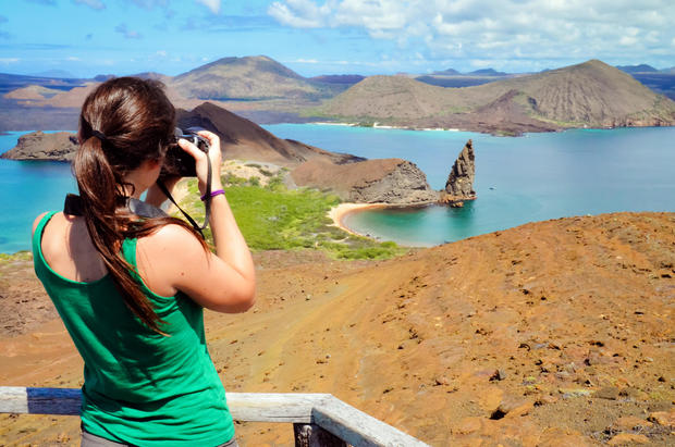 Girl taking a picture of Pinnacle Rock, Galapagos 