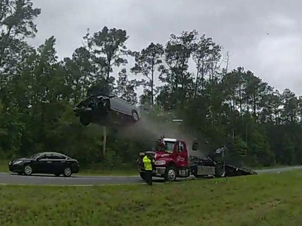 A car is seen on body camera video flying through the air after driving off a flatbed tow truck ramp on a Georgia highway May 24, 2023. 