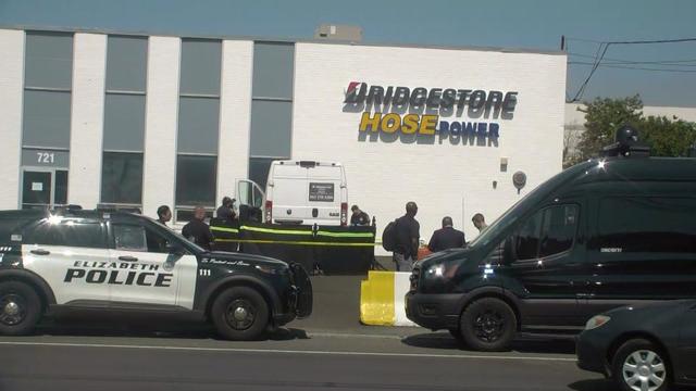 Investigators stand outside a Bridgestone Hose Power. 
